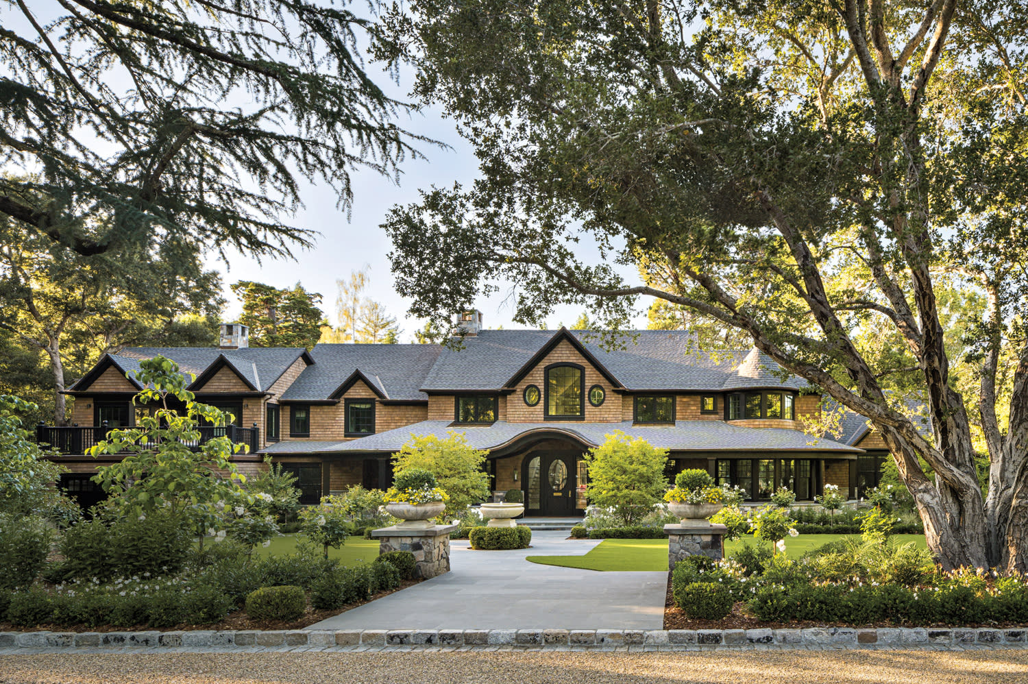 A spacious house with a driveway and lush trees lining the property, creating a welcoming atmosphere.
