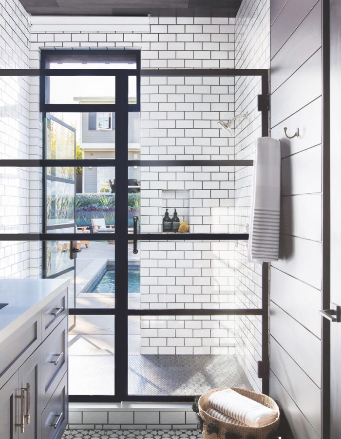 A custom shower door opens to the pool area in this chic black-and-white pool house bath in Brentwood, California, by Studio Life.Style.