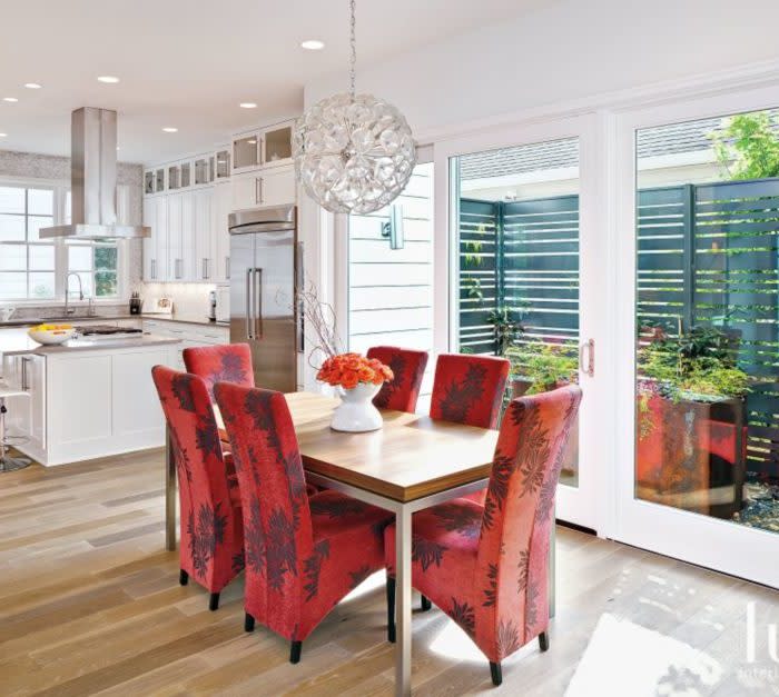 white dining room with sphere lighting and bright red floral dining chairs