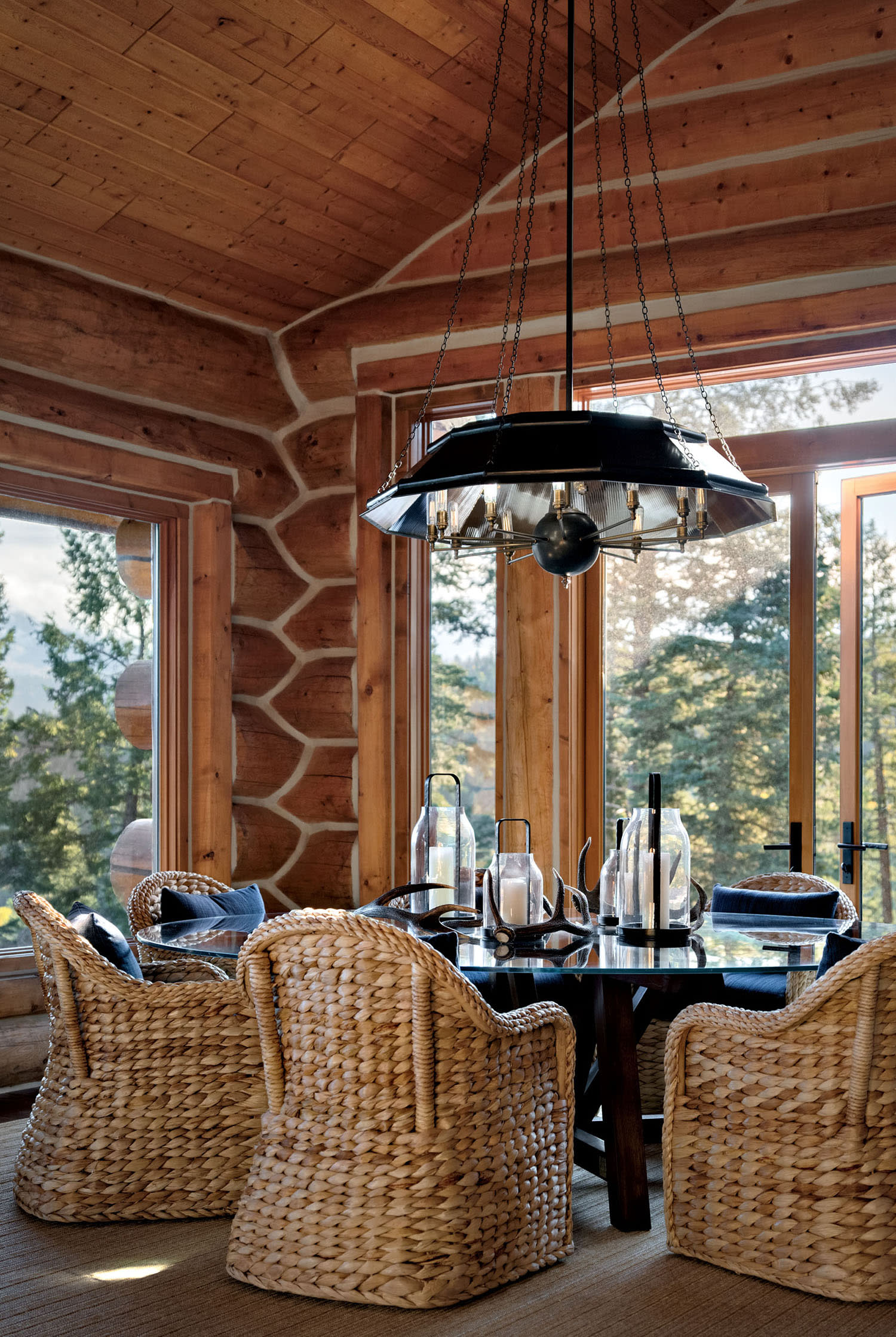 A chandelier hangs over a dining room table surrounded by chairs with navy pillows