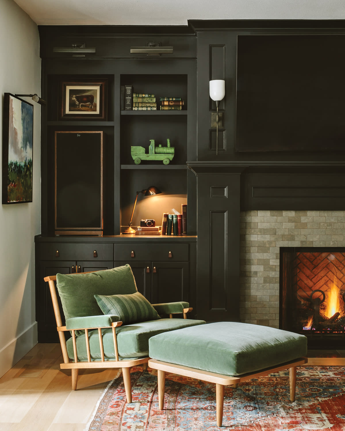 black casework sits behind an oak-framed green chair and ottoman