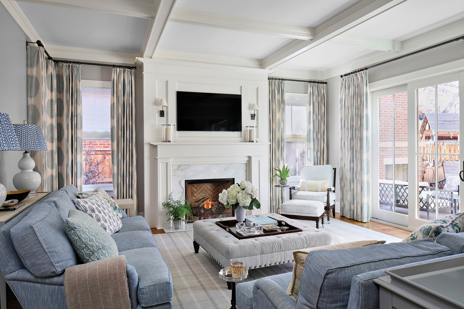 A living room with white walls, a fireplace and furnishings in a palette of light gray and white.