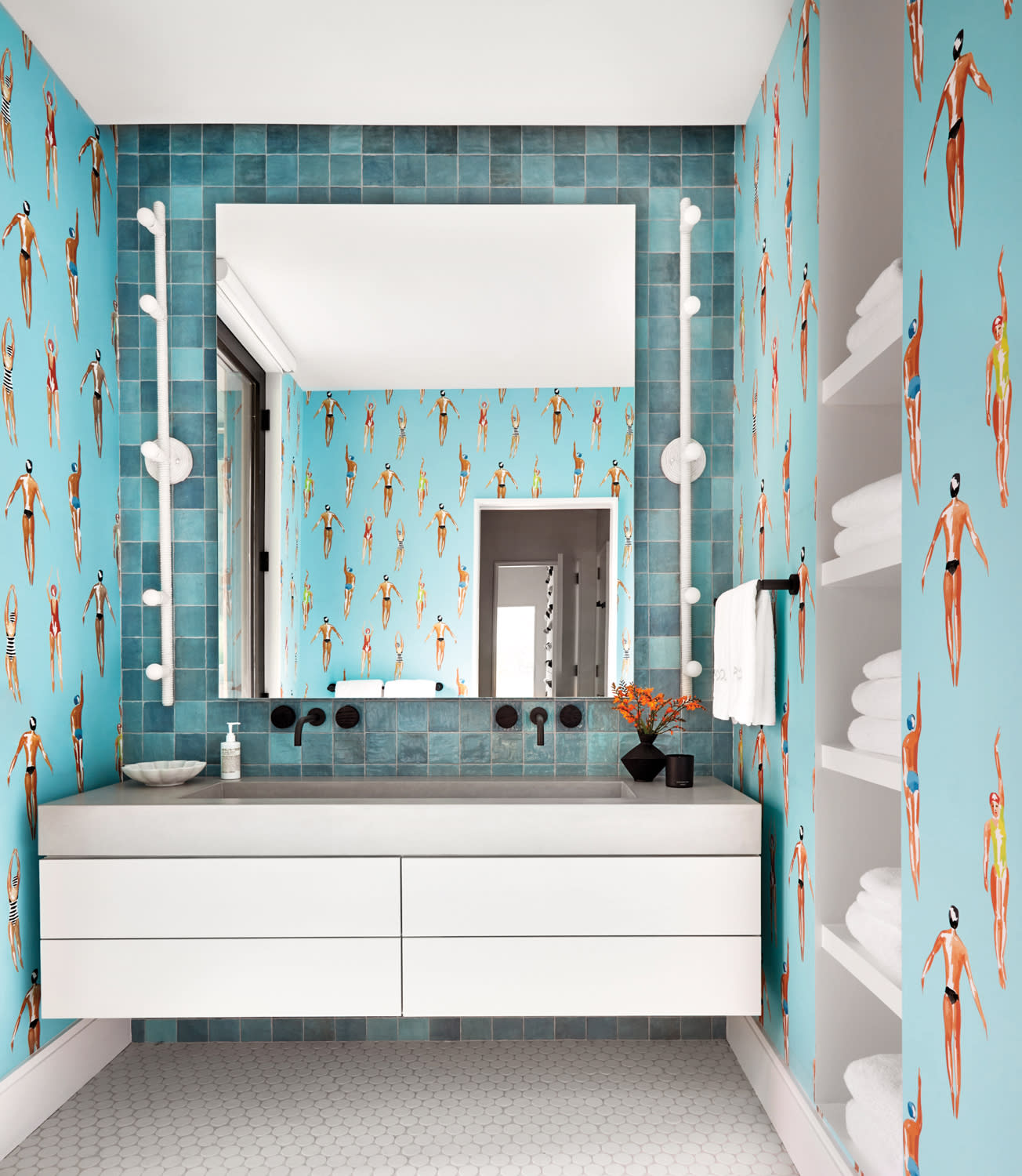 floating concrete vanity flanked by wallpaper with vintage swimmers