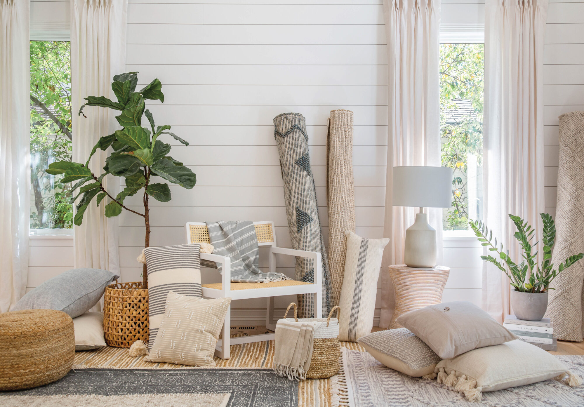 stacks of pillows and fabric with plants in the corners