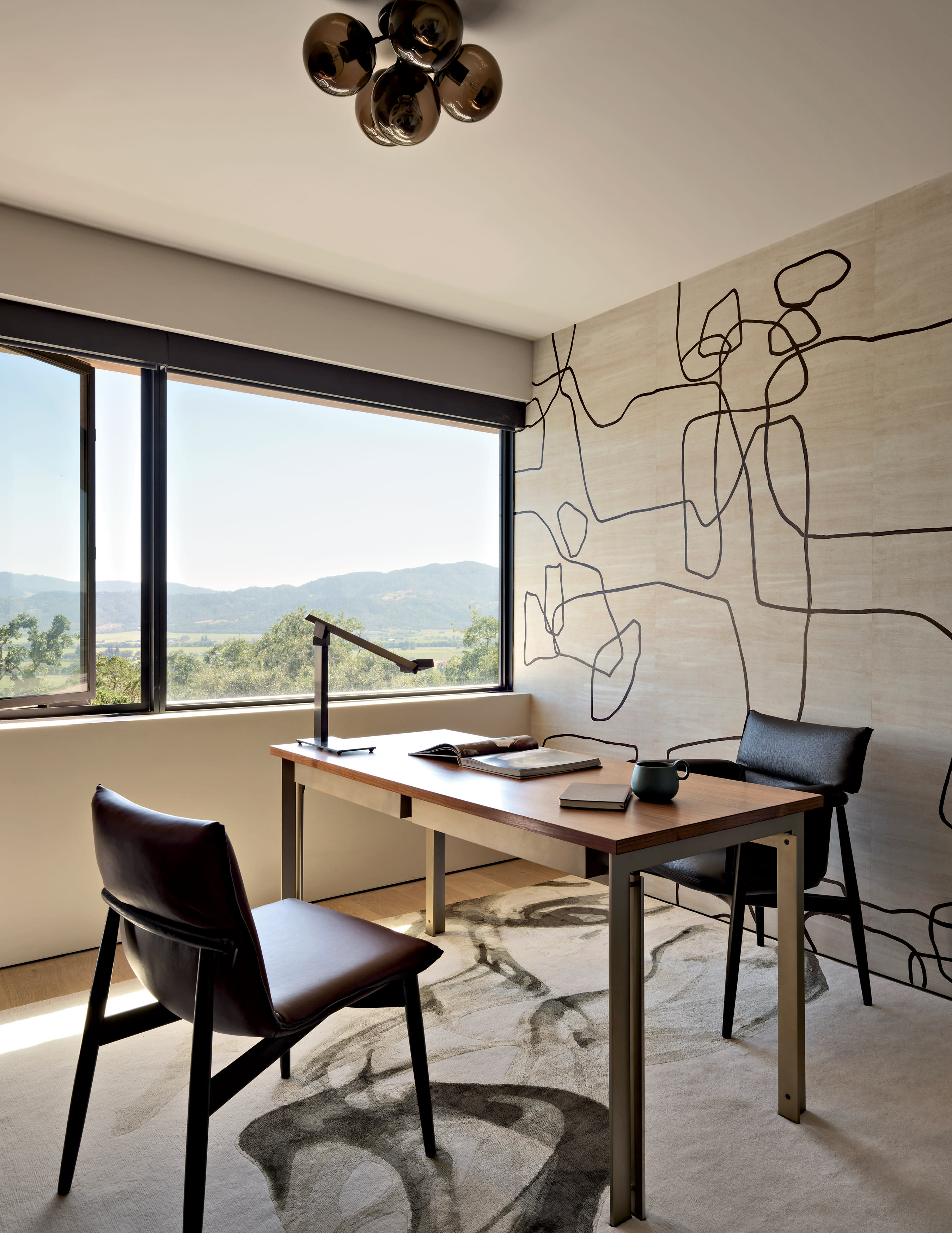 An abstract wallcovering at the back of an office decorated with a desk with a chair on either side.