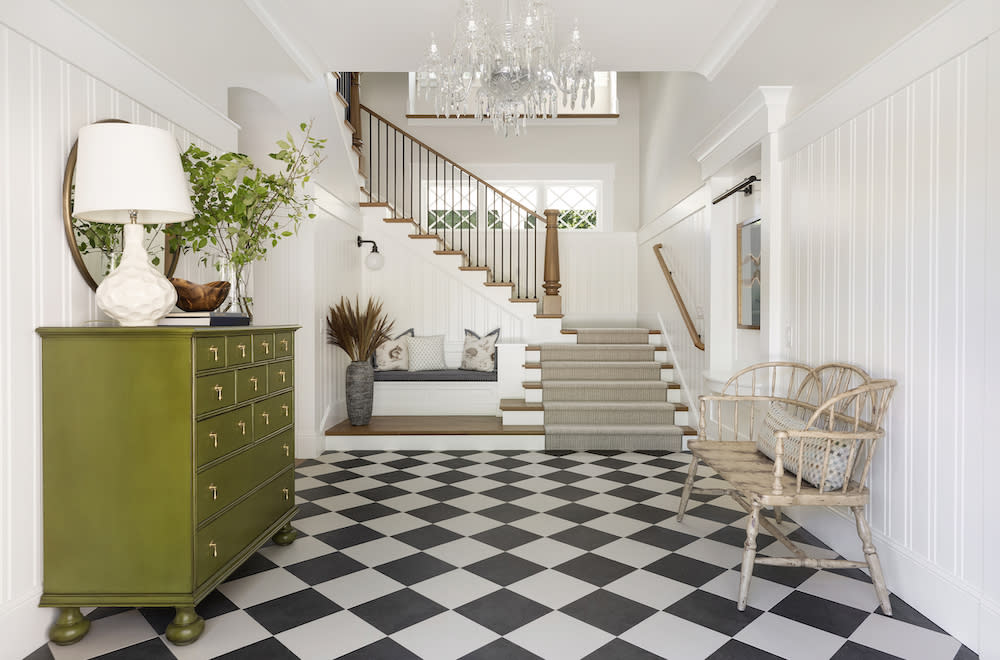 The black and white checkered floor and cozy seating nook add unexpected interest to this entry way. 