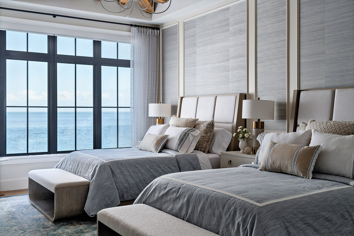 Luxurious bedroom with two neatly made beds with gray linens and plush cushions