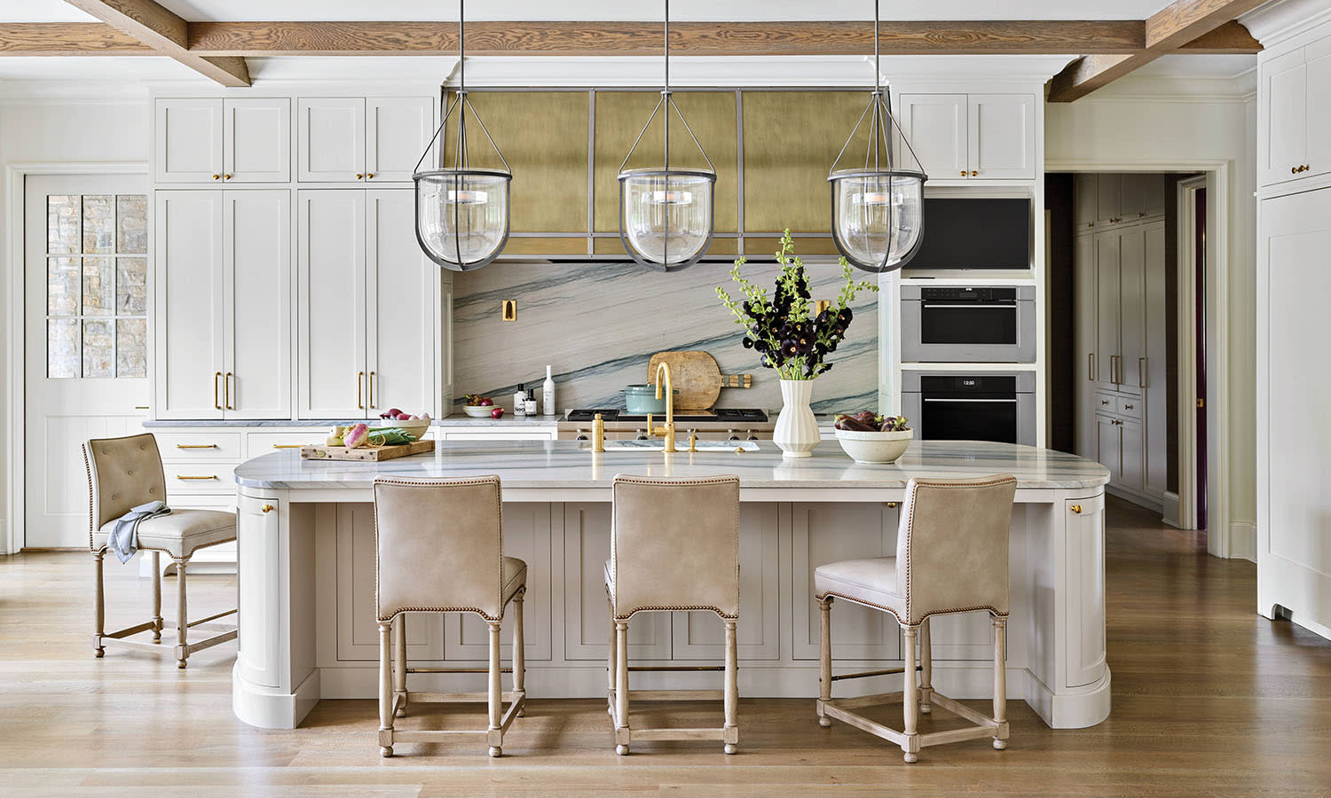 traditional meets contemporary kitchen with white cabinetry and a brass hood