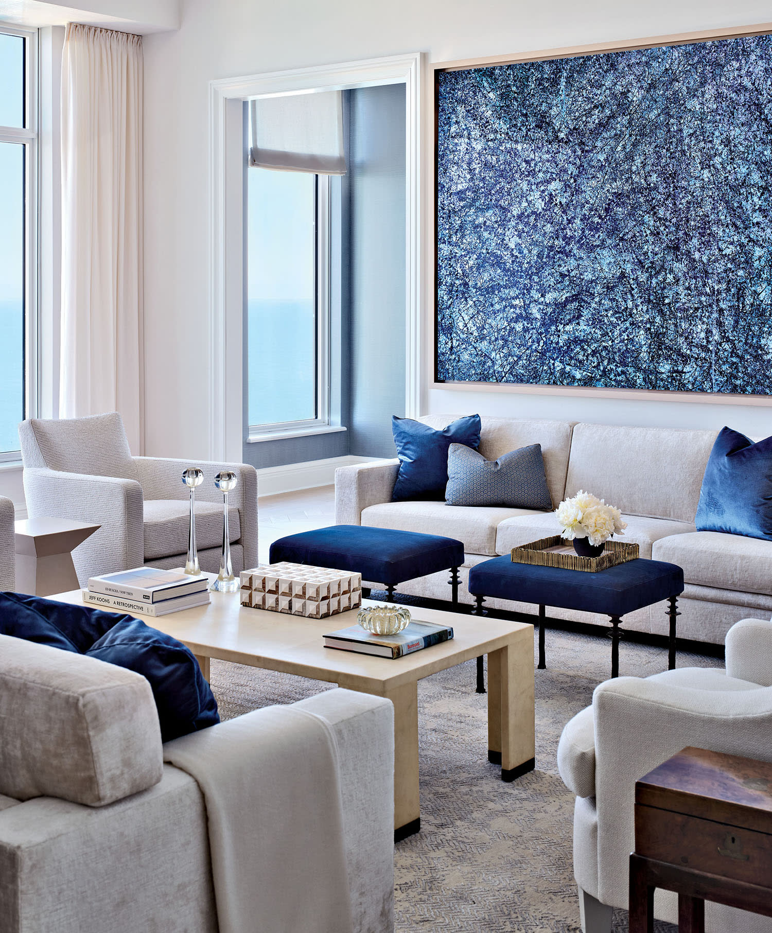 A living room with white walls and couches with blue accent pillows, arranged around a coffee table.
