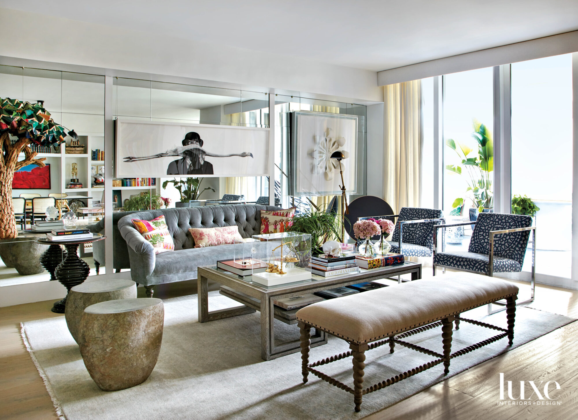 eclectic living area with gray tufted sofa, mirrored wall and artwork