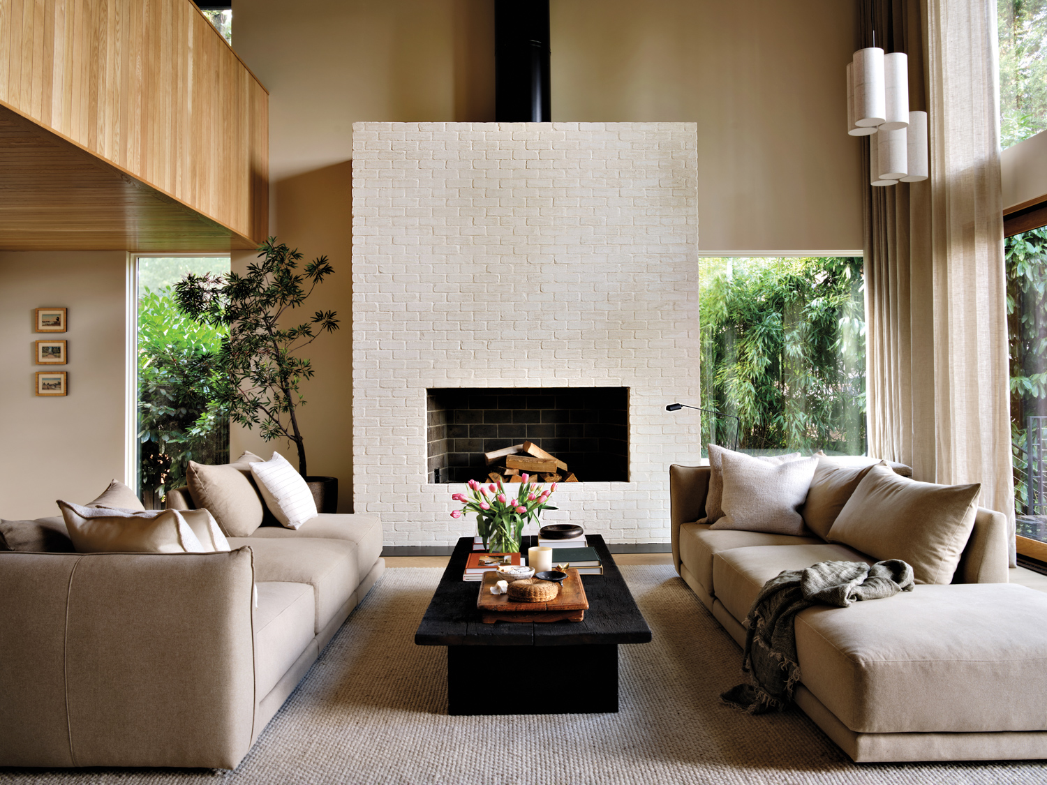 cozy living room with two neutral sofas, black coffee table and white brick fireplace