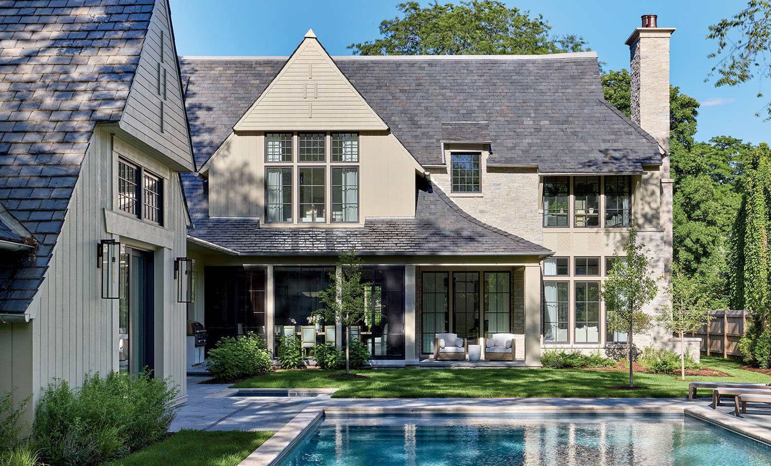 English-inspired gabled house exterior with a large pool