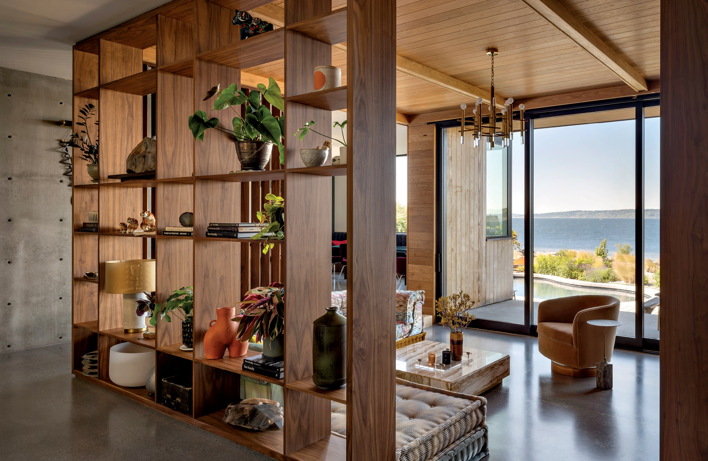 an open-shelving partition allows views outside to the water in the entry of a Brutalist home