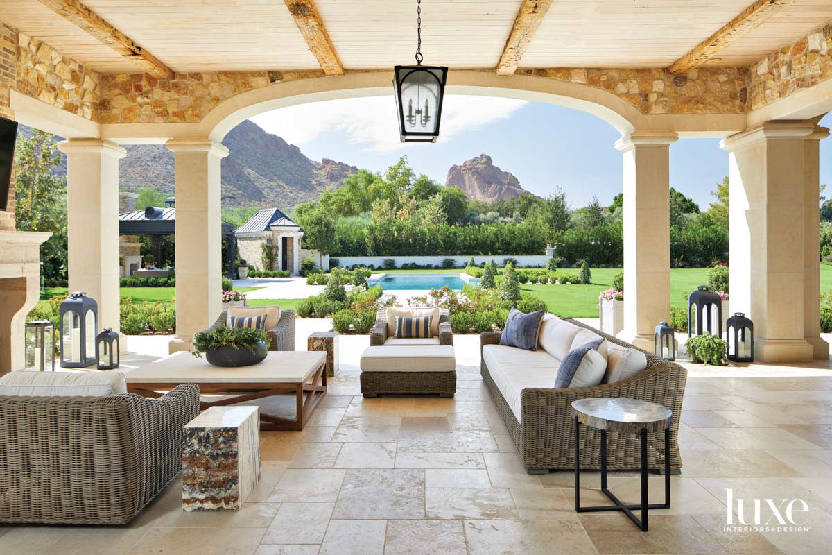 An outdoor pavilion with outdoor furniture and a pool in the background.