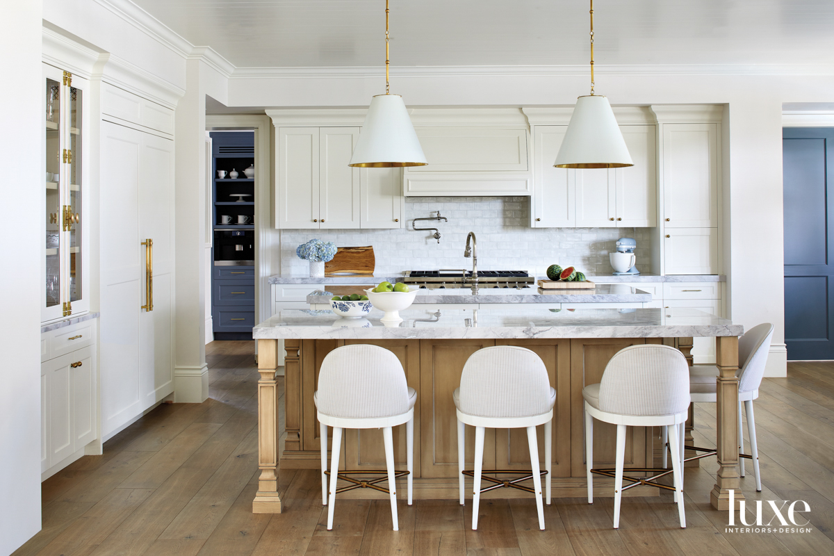 Counter stools lined up at a light wood island with a quartz top.