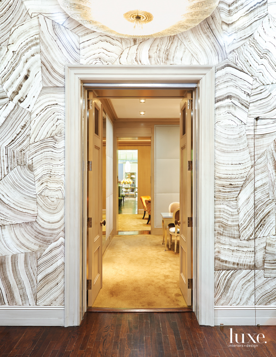 doorway with wallcovering around the door and chandelier