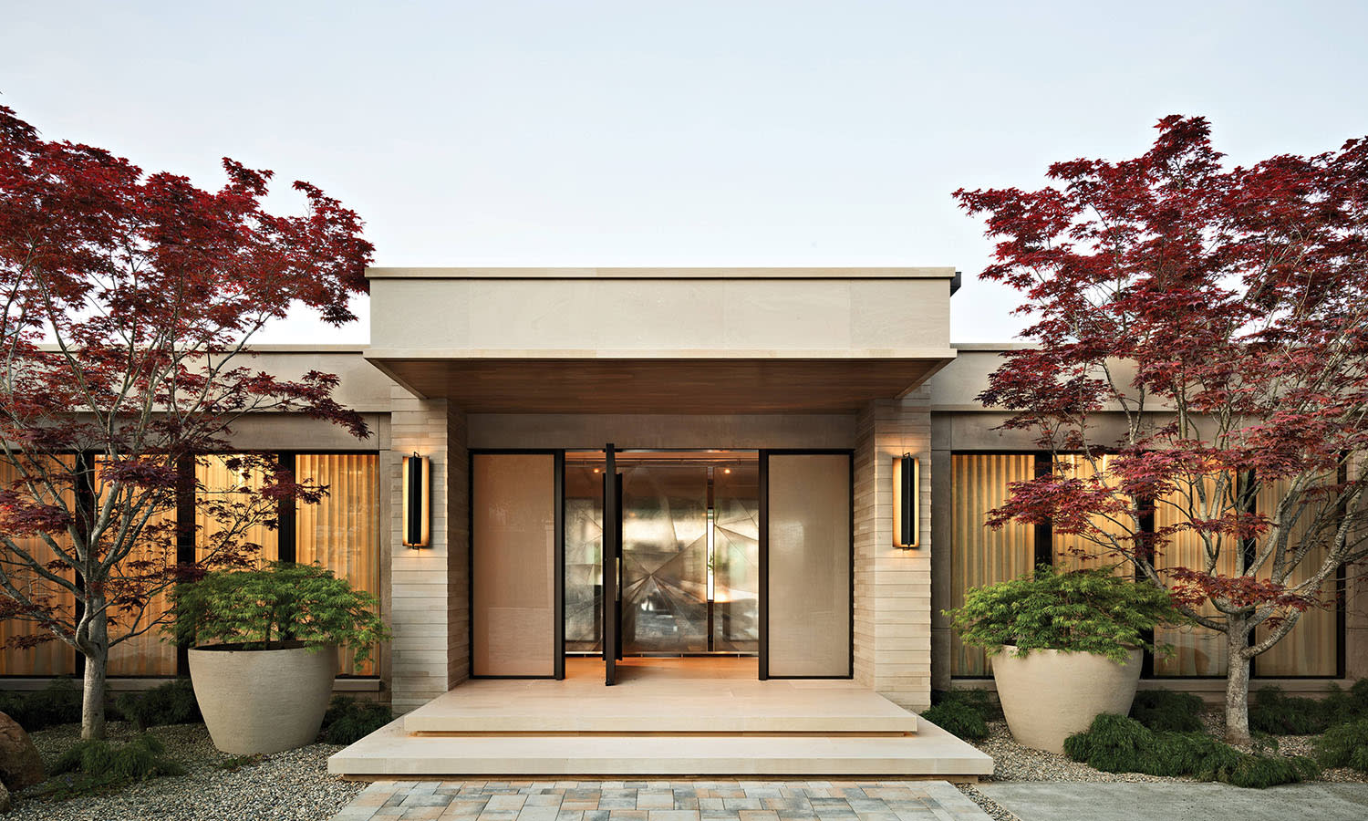 limestone home exterior flanked by Japanese maple trees
