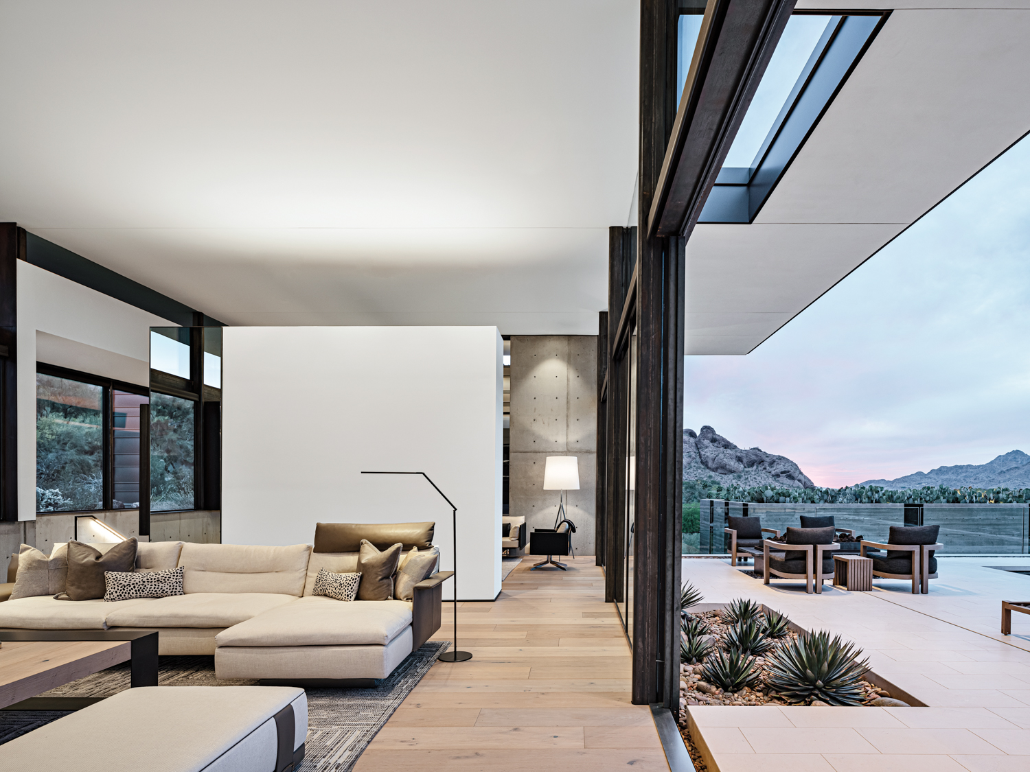 A living room with a large white sectional that opens to a patio.