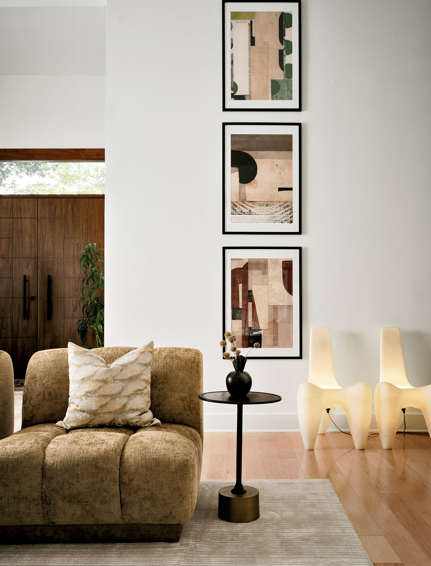 living room with a trio of abstract artworks and a pair of electrified fiberglass chairs