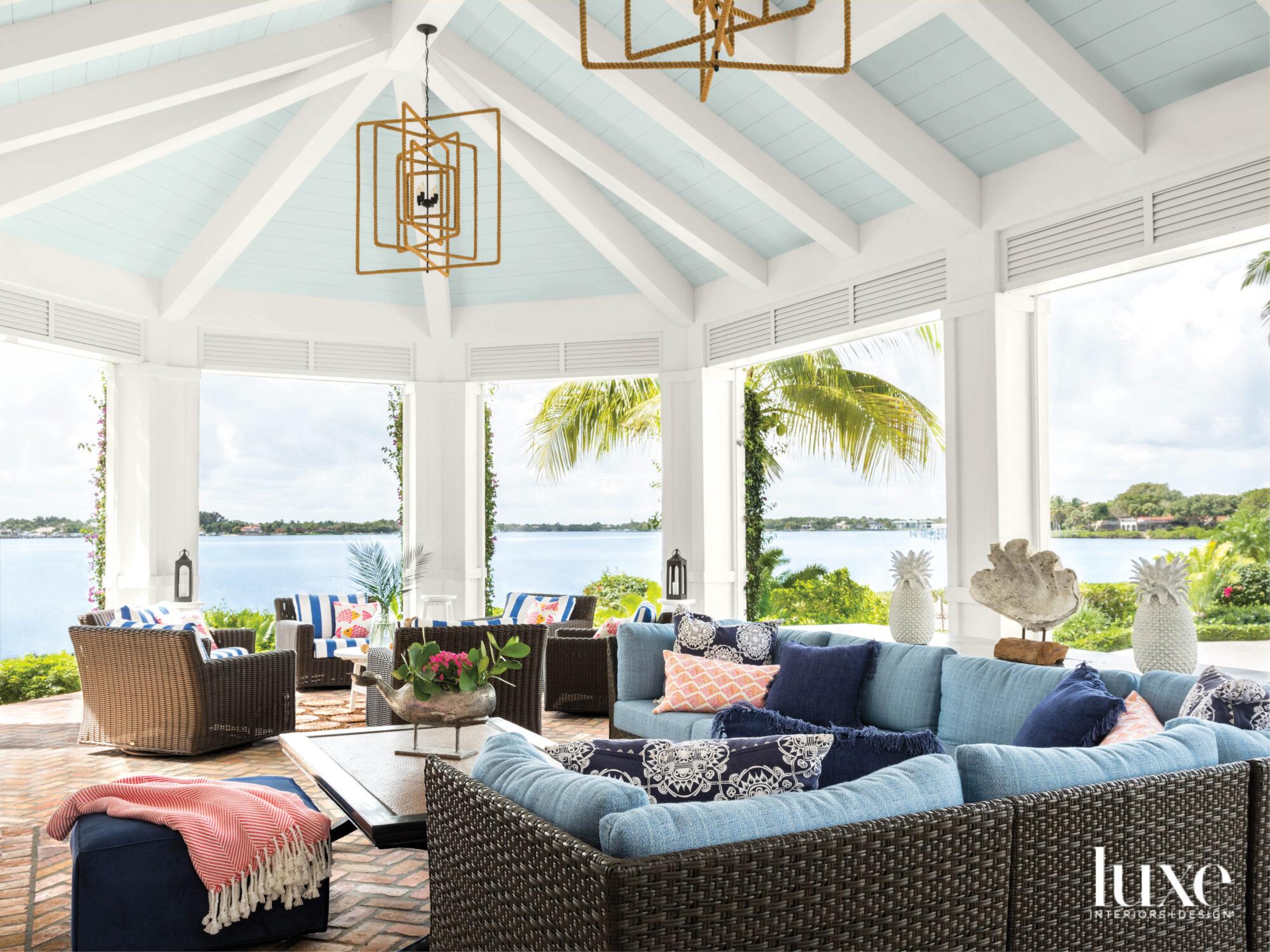 loggia overlooking waterway with light blue ceiling, rope lantern chandeliers and blue wicker furnishings