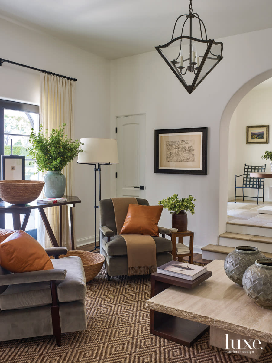 library with two velvet armchairs atop a patterned rug featuring a hanging pendant