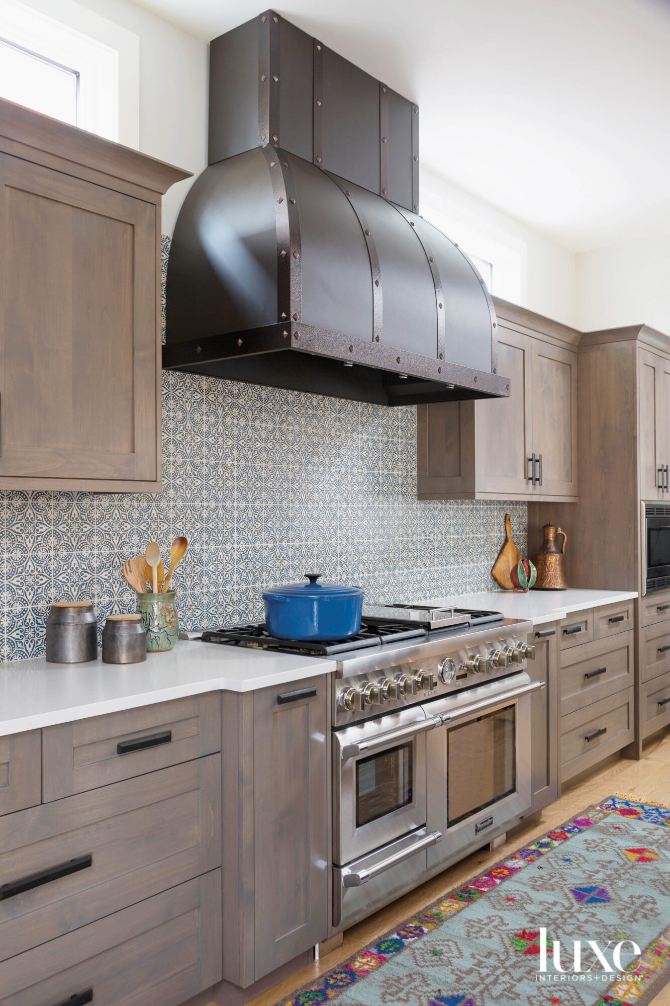 A large range hood with metal strapping is the focal point of the kitchen.