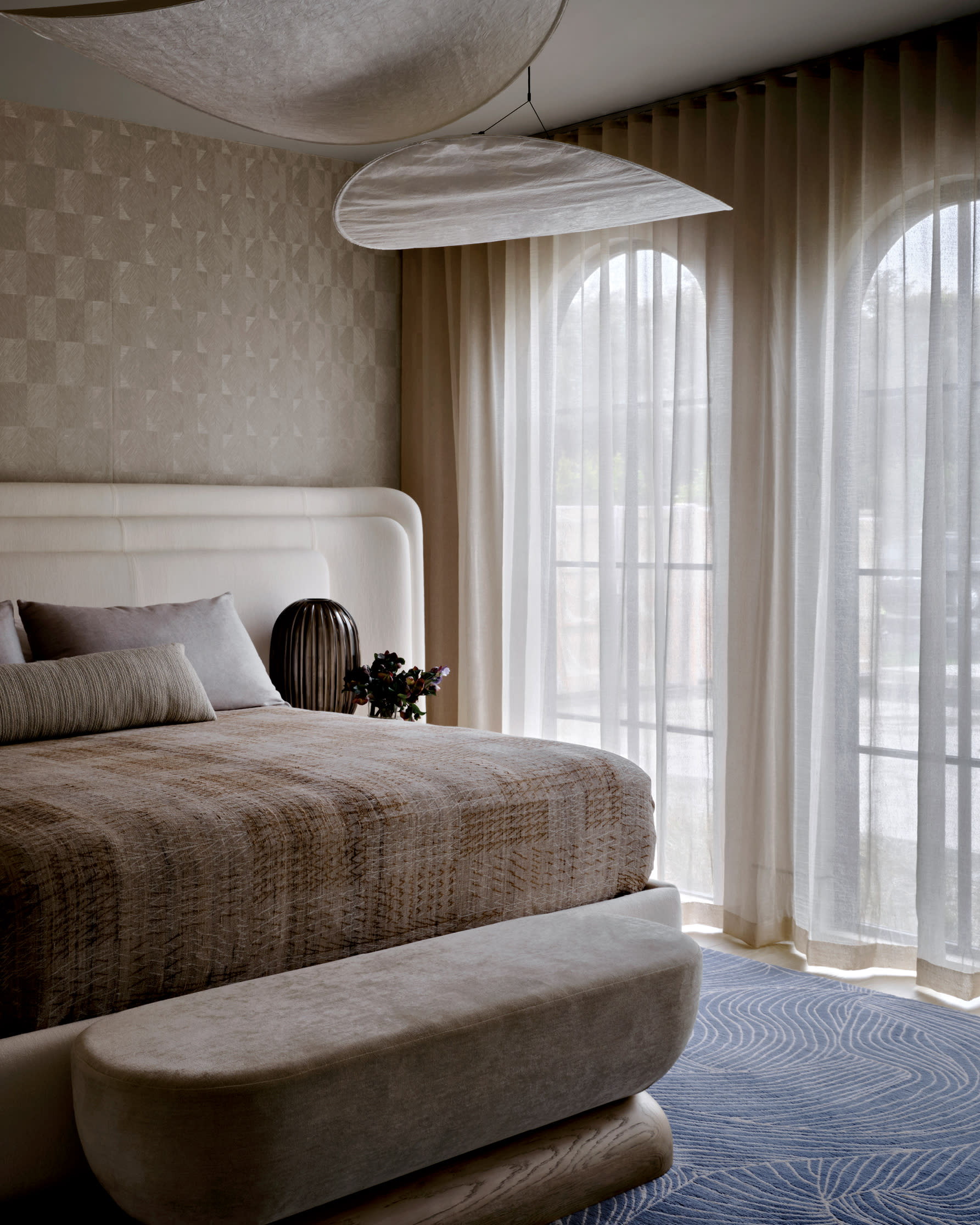 modern bedroom in neutral tones, including a brown wallcovering, brown linens and blue flooring