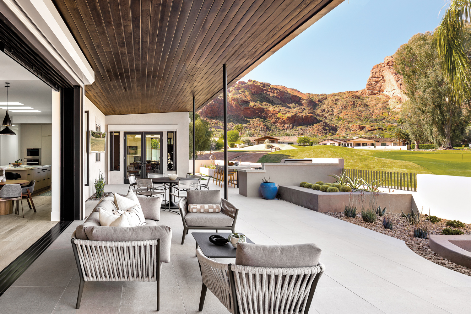 patio with dining table, sofa and lounge chairs looking out on a golf course and mountains