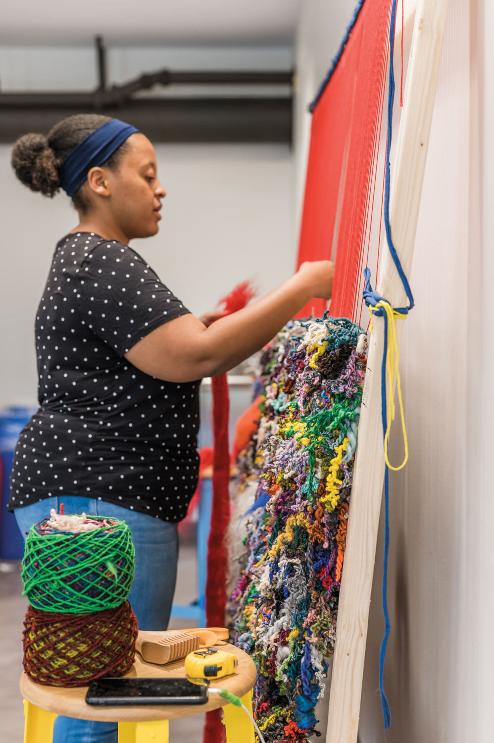 artist Bryana Bibbs weaving a colorful work on a frame loom