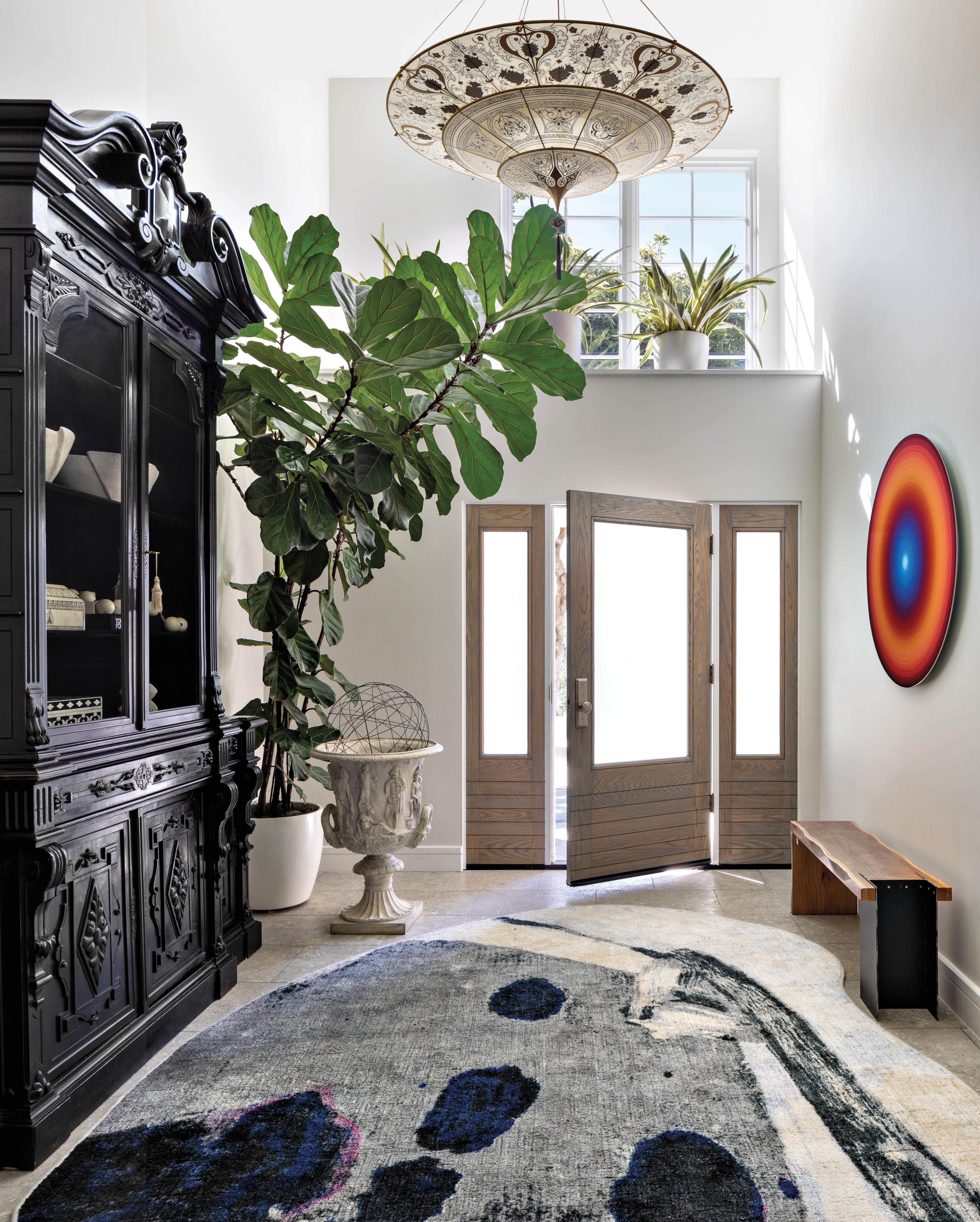 airy entryway with statement light fixture and black armoire 