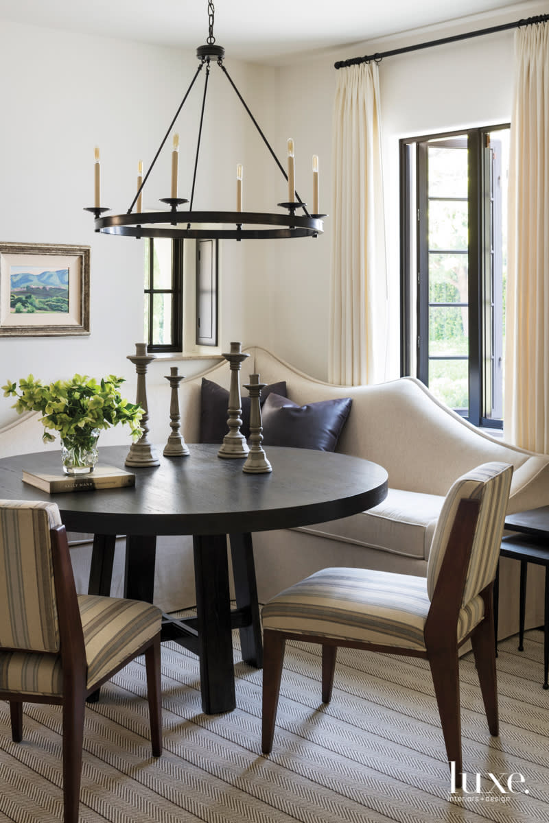 a corner of the living room with a scalloped back custom banquette and table and fabric chairs