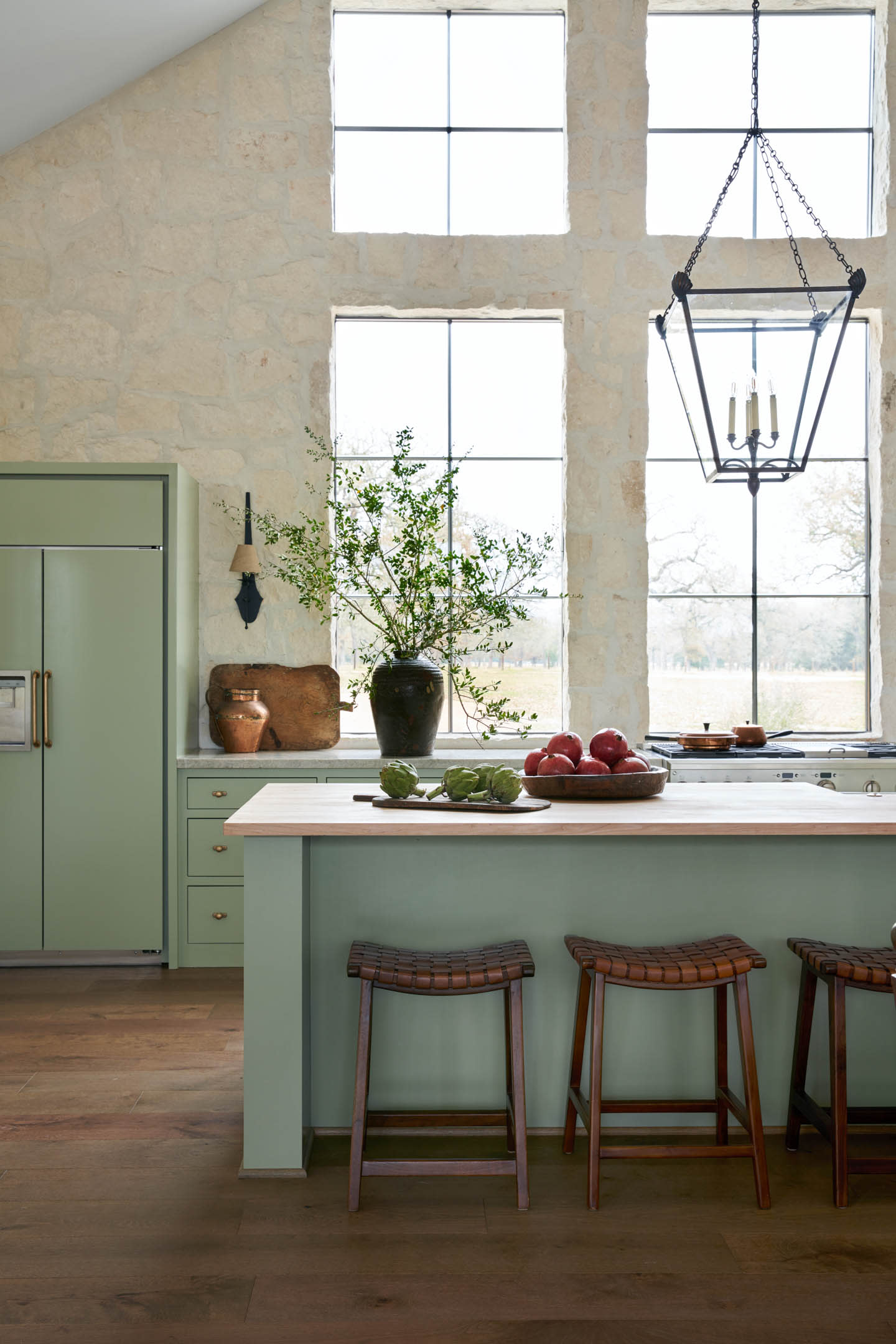 light-filled kitchen with green lower cabinets and matching island 