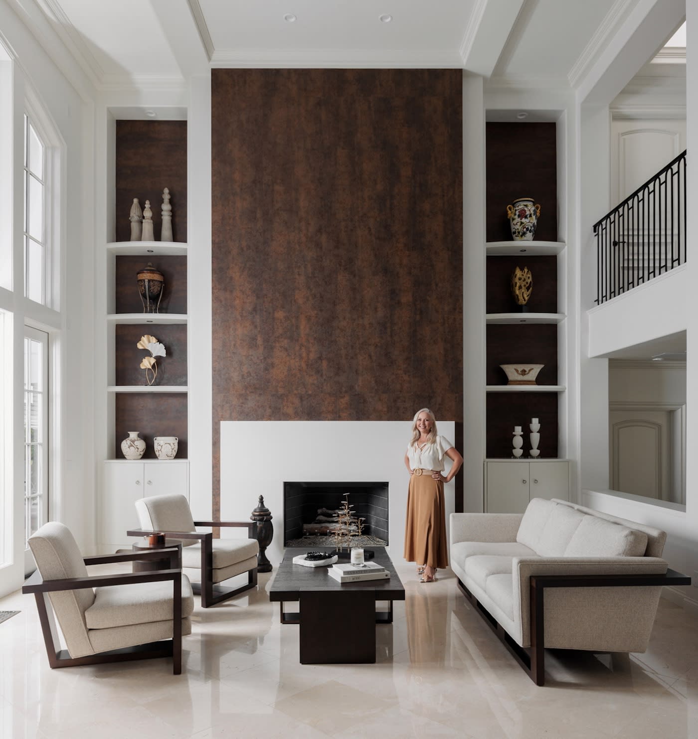 Samia Verbist poses near a fireplace, surrounded by a stylish living room setting.