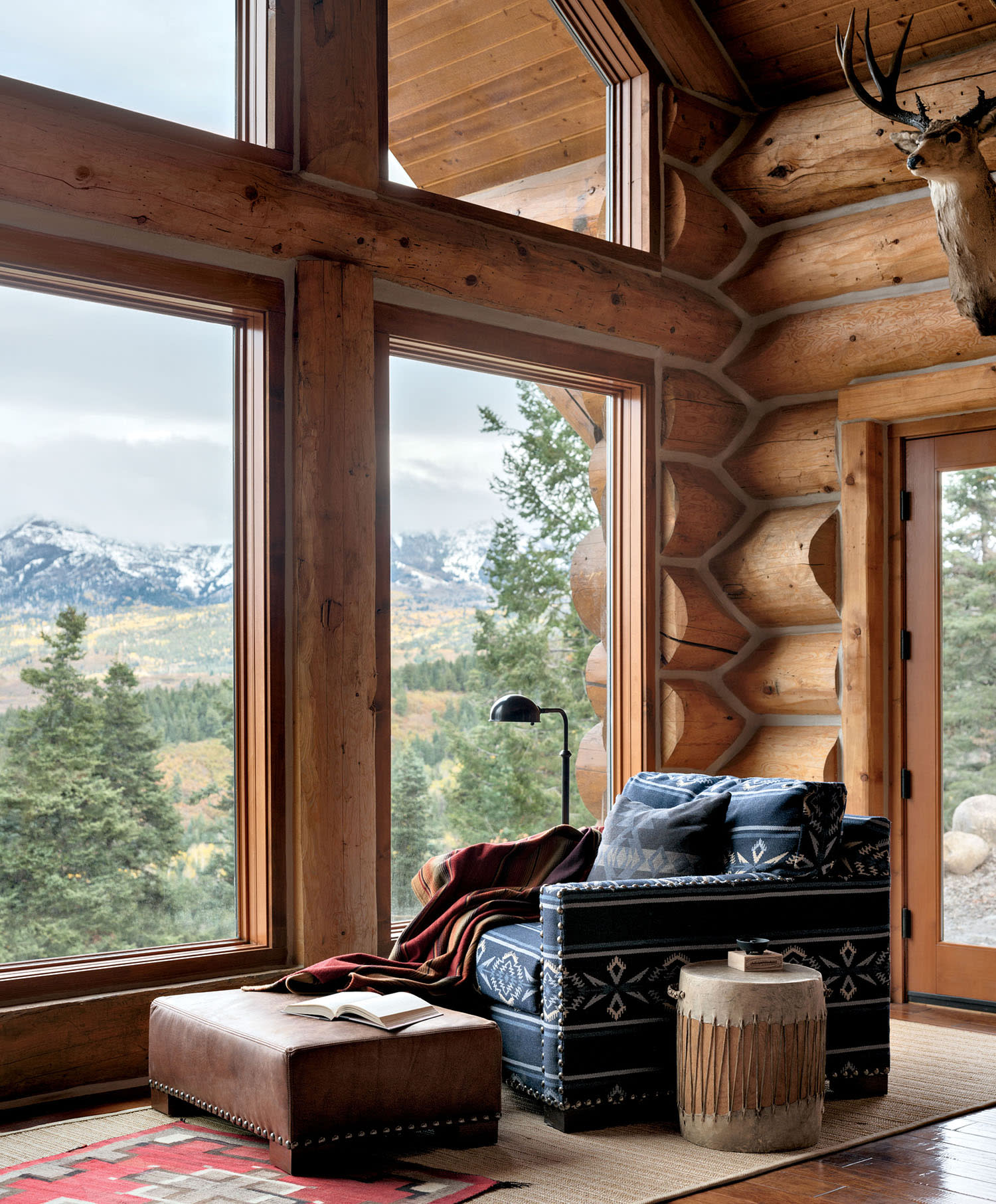 navy printed armchair sits in a corner near large windows overlooking the mountains in this living room