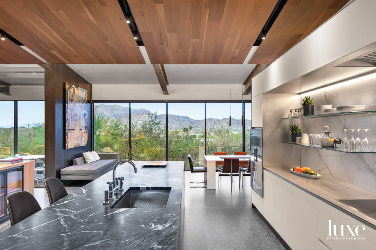 A minimalist kitchen with a black marble-toped island.