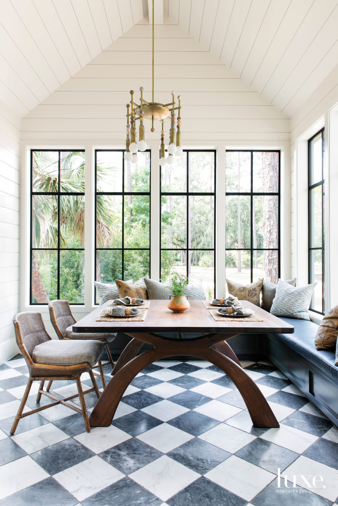 Dining table surrounded by windows atop checkerboard floors