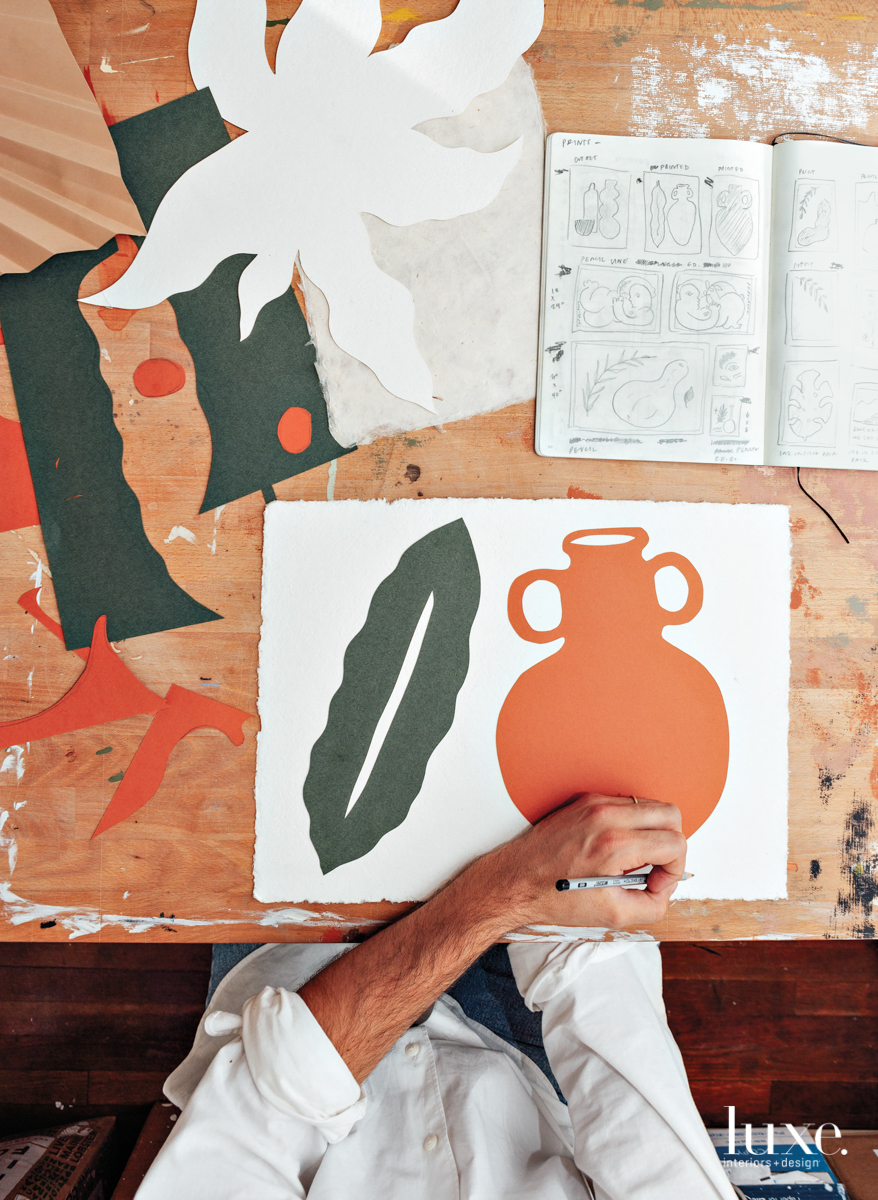 alvarez's hand working on another piece of art, orange painting of a pot