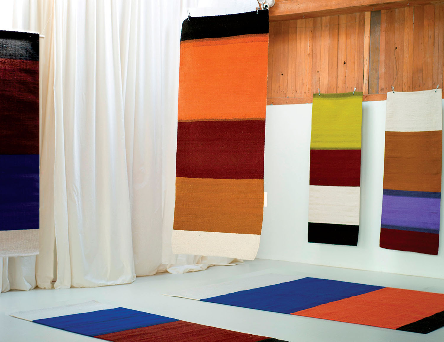 Colorful textiles are displayed on the walls and floor of a gallery space.