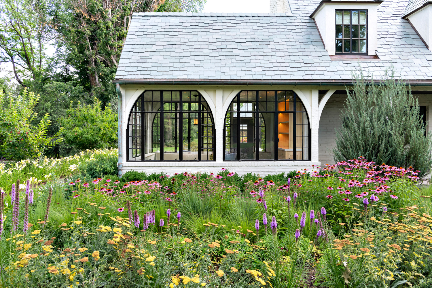 exterior of Tudor cottage surrounding by native Colorado flowers