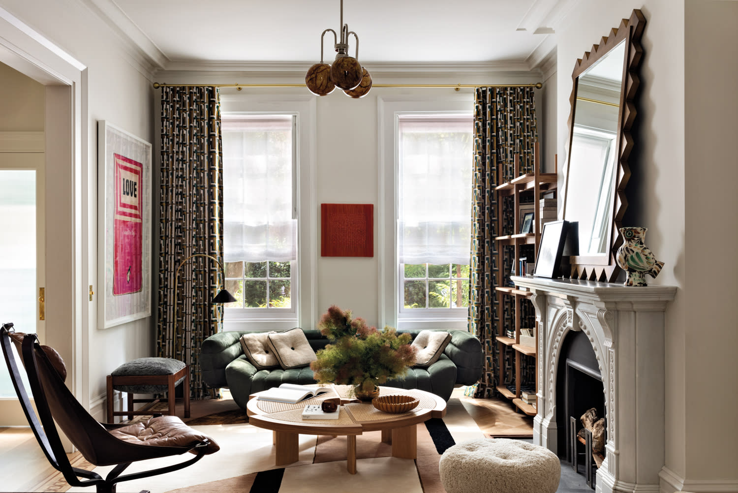 Stylish living room with green sofa, round wooden coffee table, and modern art. Sunlight filters through two large windows, creating a cozy atmosphere.