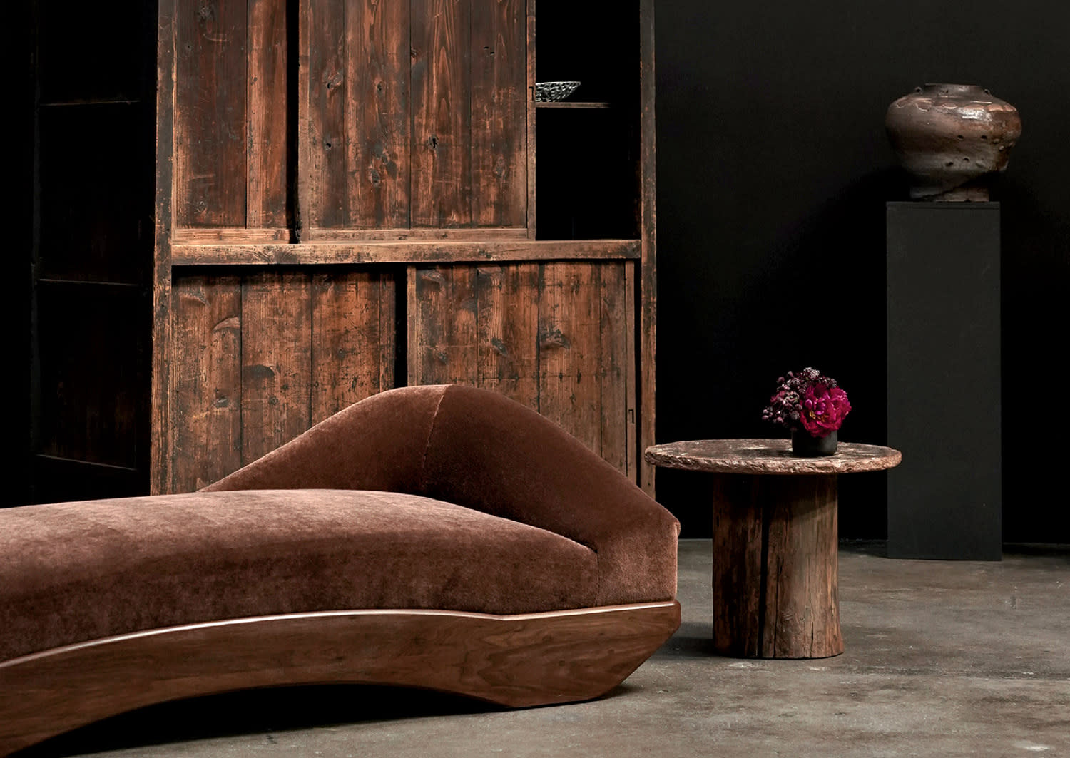 brown chaise in front of a rustic cabinet