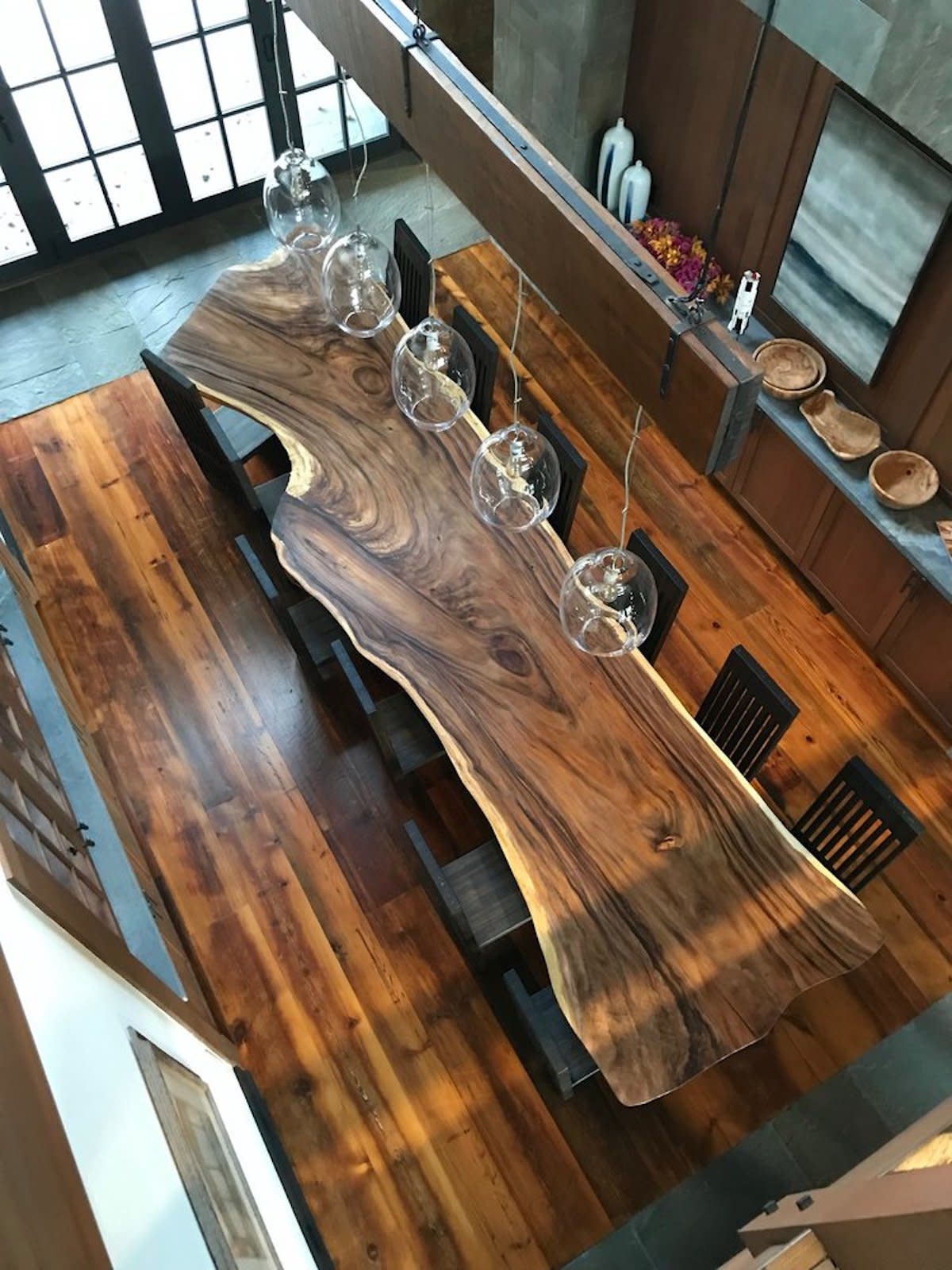 Live edge dining table with sophisticated lighting fixture.