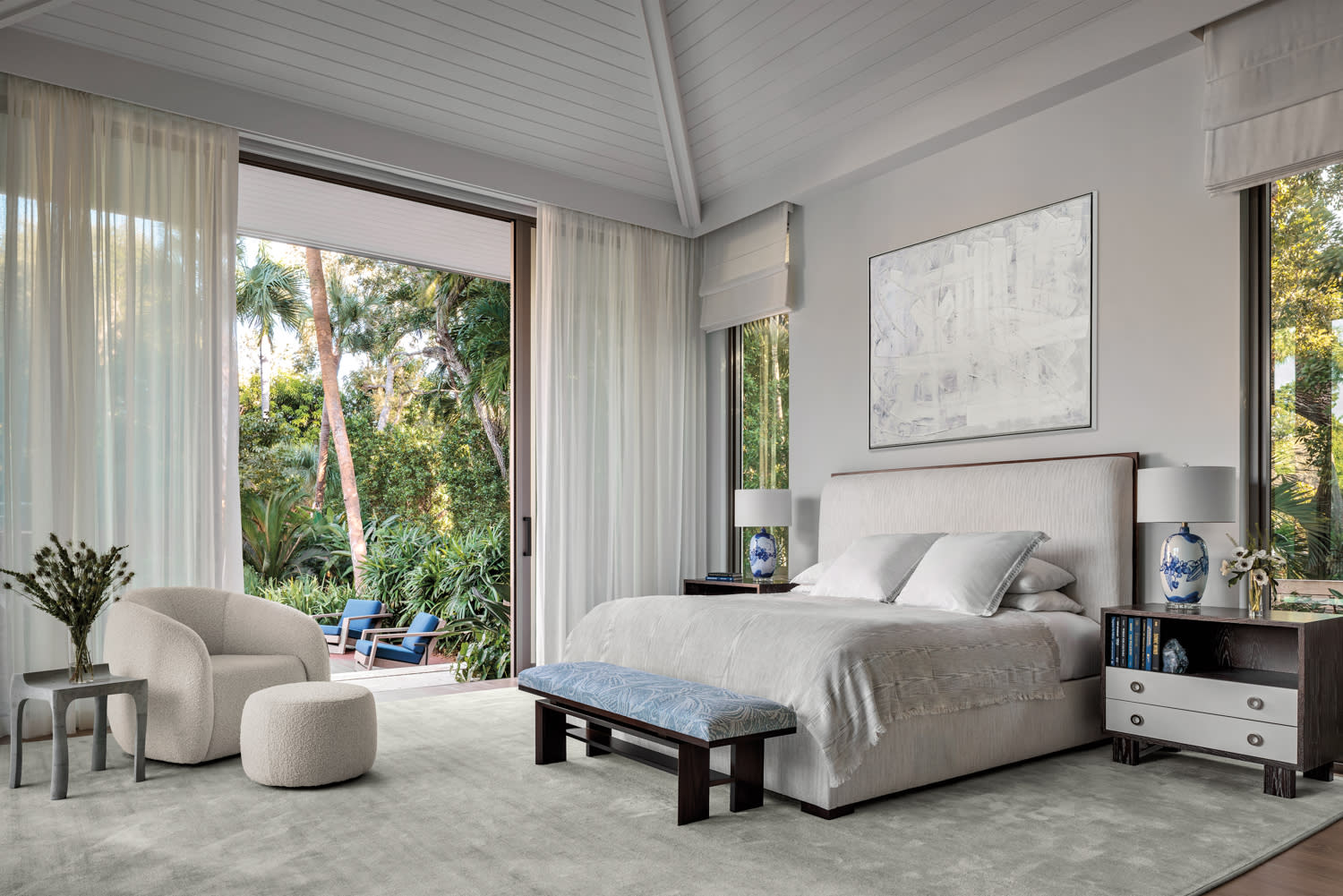 contemporary bedroom with a gray rug and doors opened to a patio outside