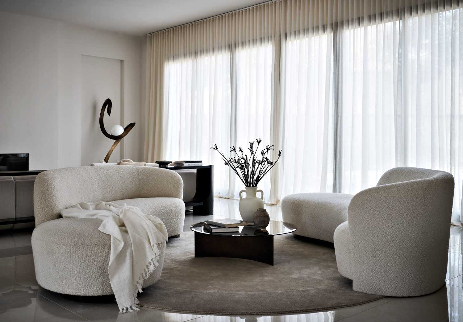 monochrome living room with curving white sofas and a sculpture