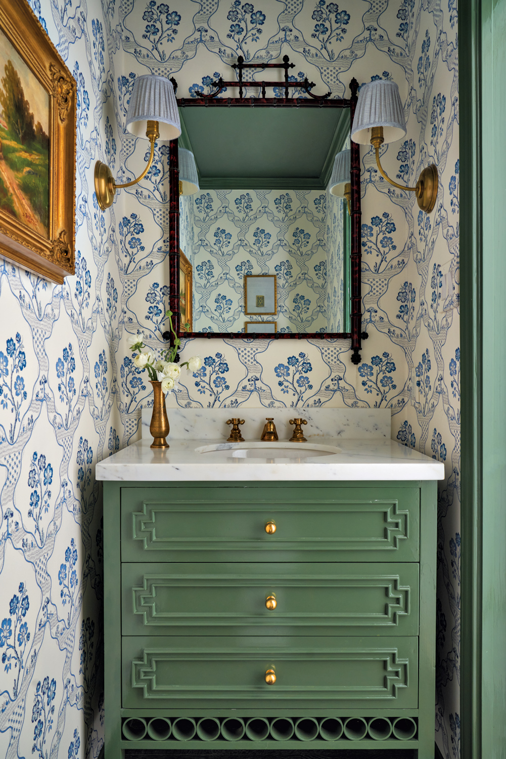 Blue, floral pattern wallcovering in powder bathroom with a sage green vanity and trim