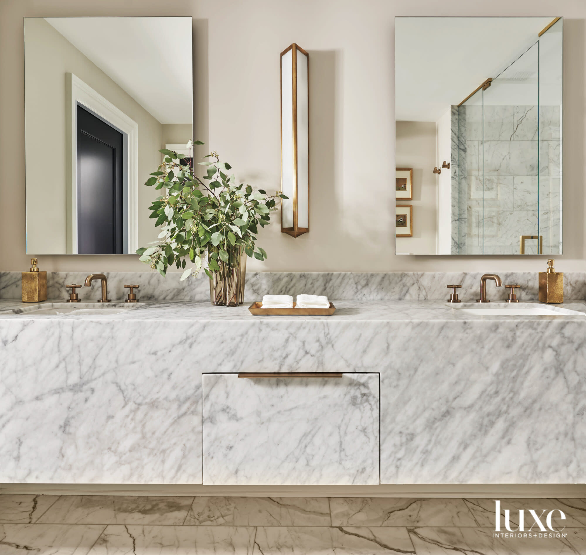 A marble countertop in a bathroom. Two mirrors hang above the dual sinks.