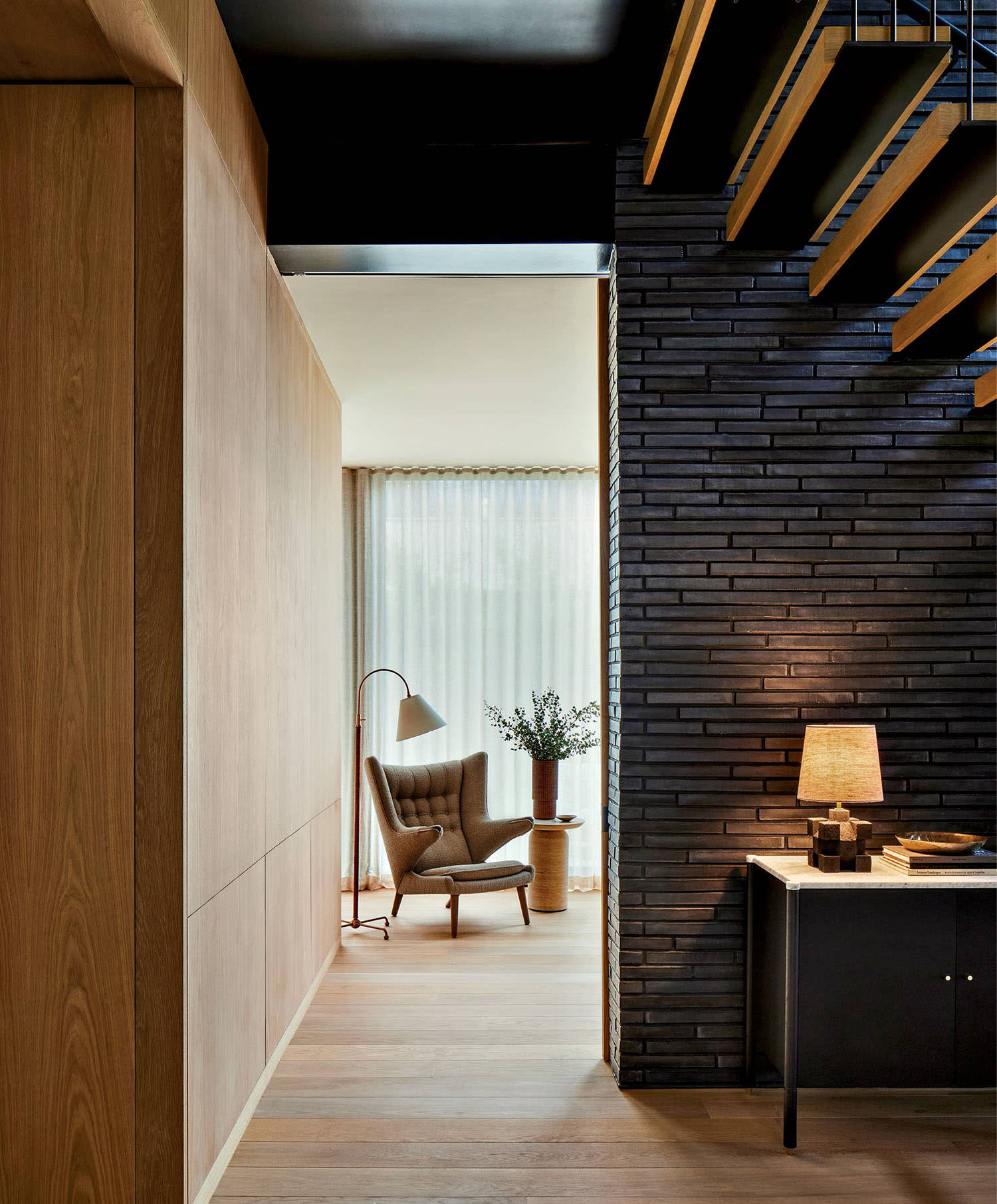 home office doorway flanked by a black brick wall underneath a stairway