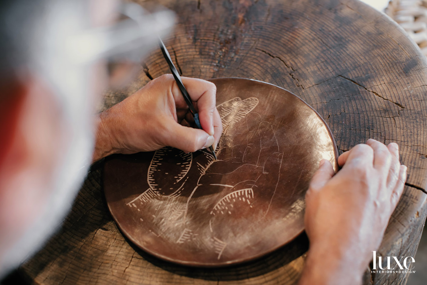 A hand etching a plate