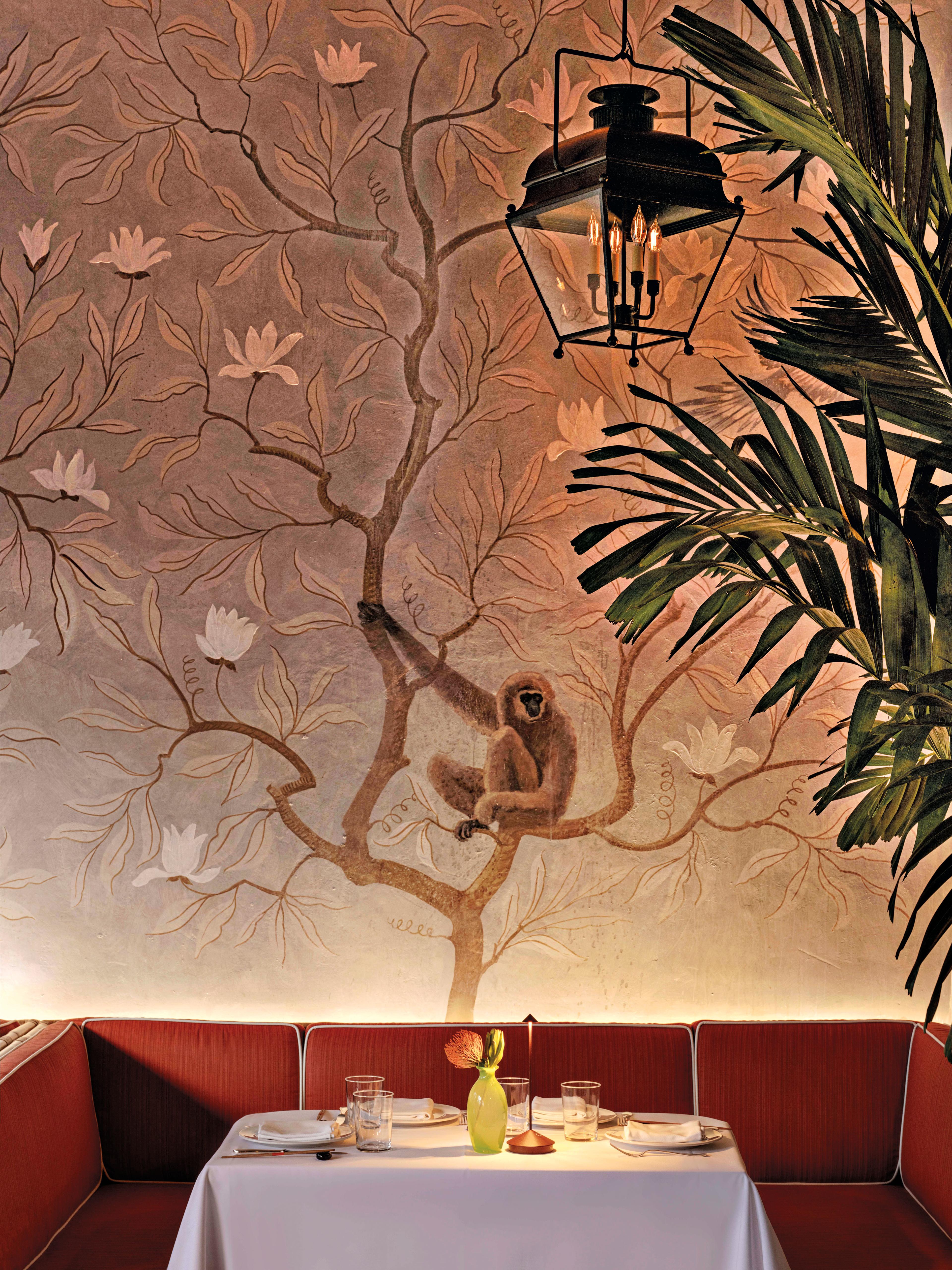 le colonial naples restaurant table with red banquette and tree monkey wallpaper