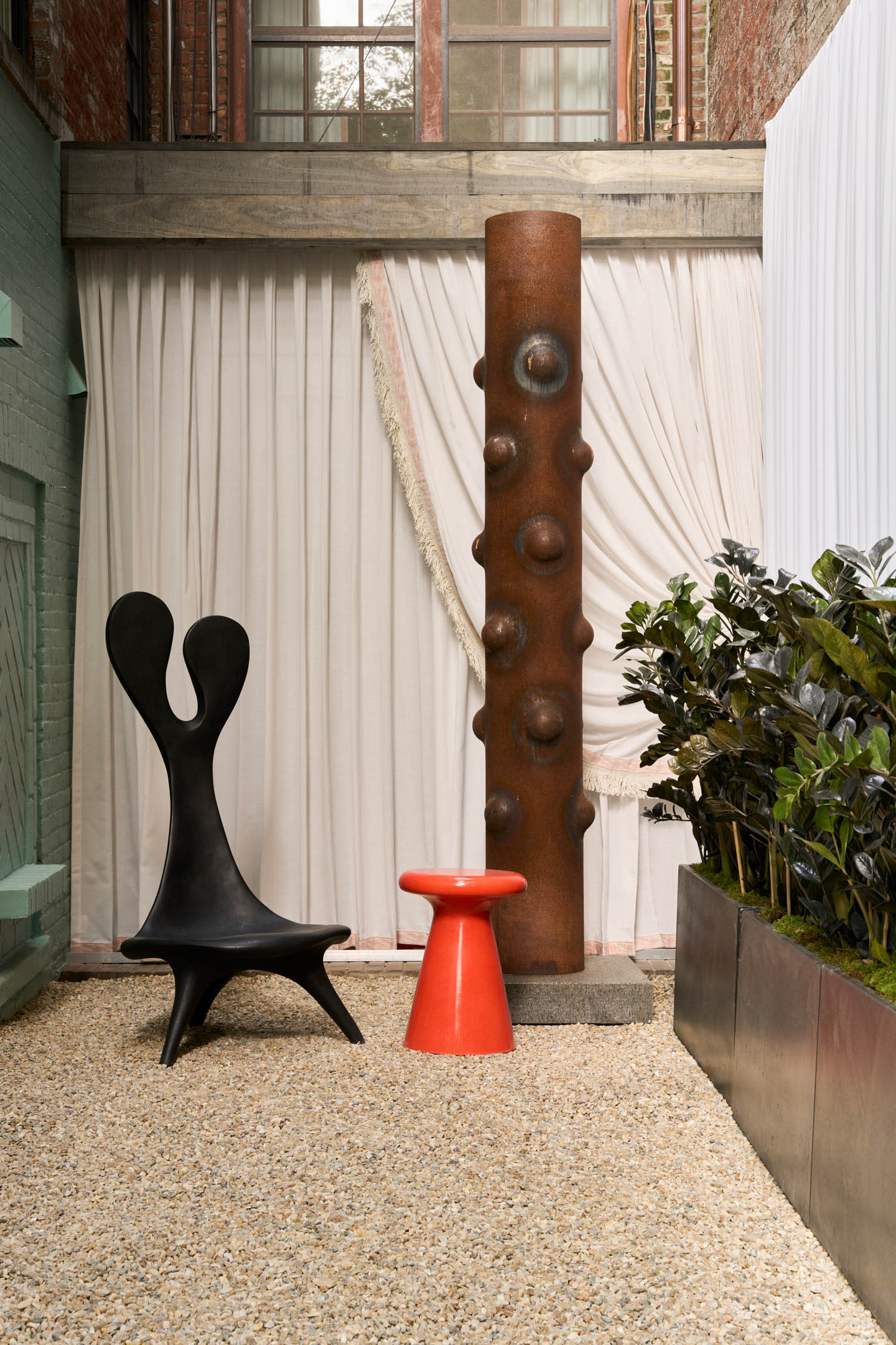 Kips Bay New York showhouse 2025 garden terrace with a Brutalist sculpture and a three-legged chair